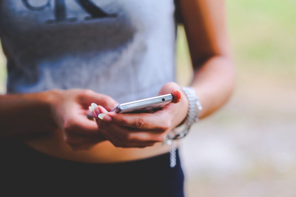 Person texting on a smartphone, wearing jewelry.