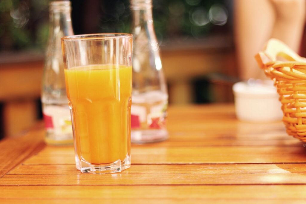 Glass of orange juice on wooden table.