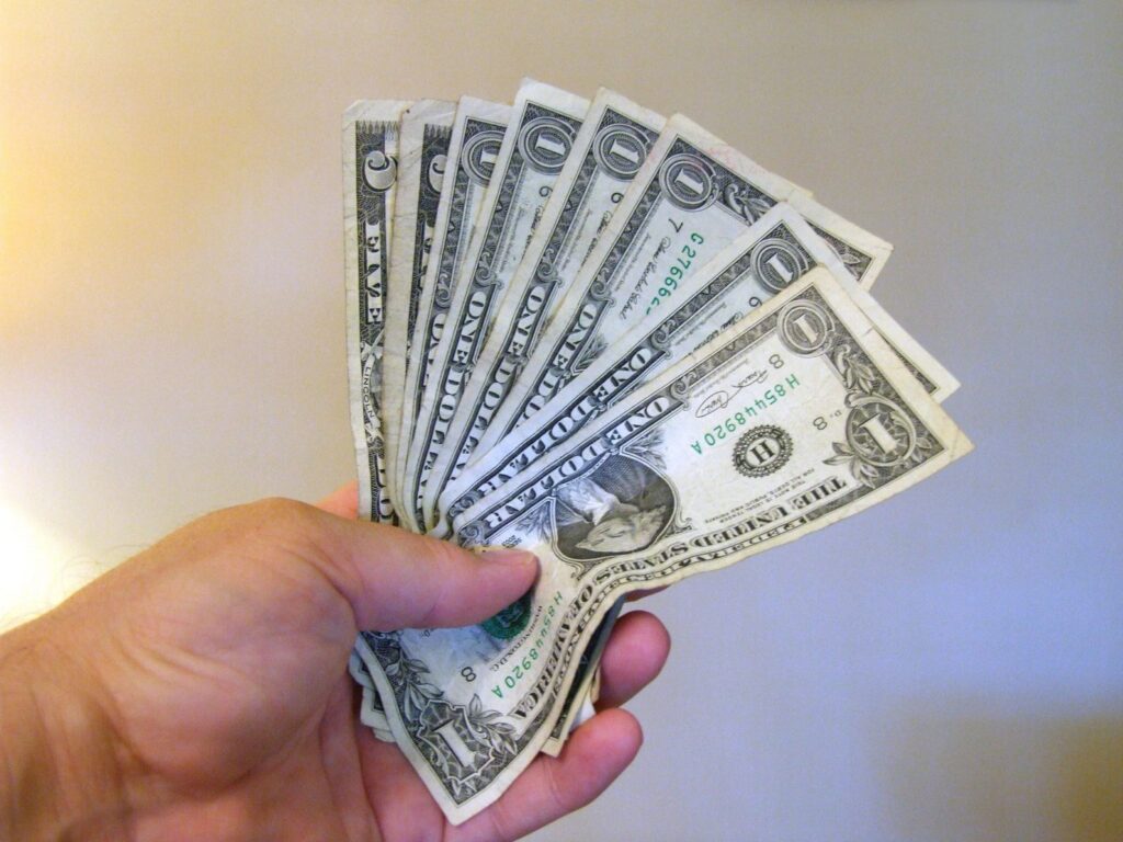 Hand holding several one-dollar bills.