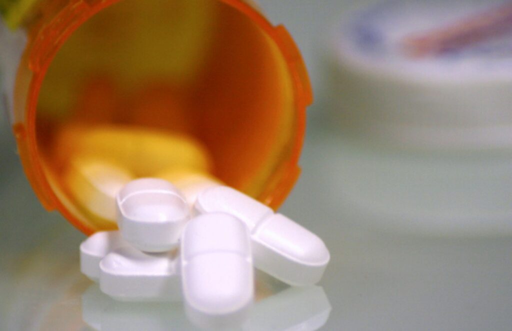 Prescription pills spilling from orange bottle.