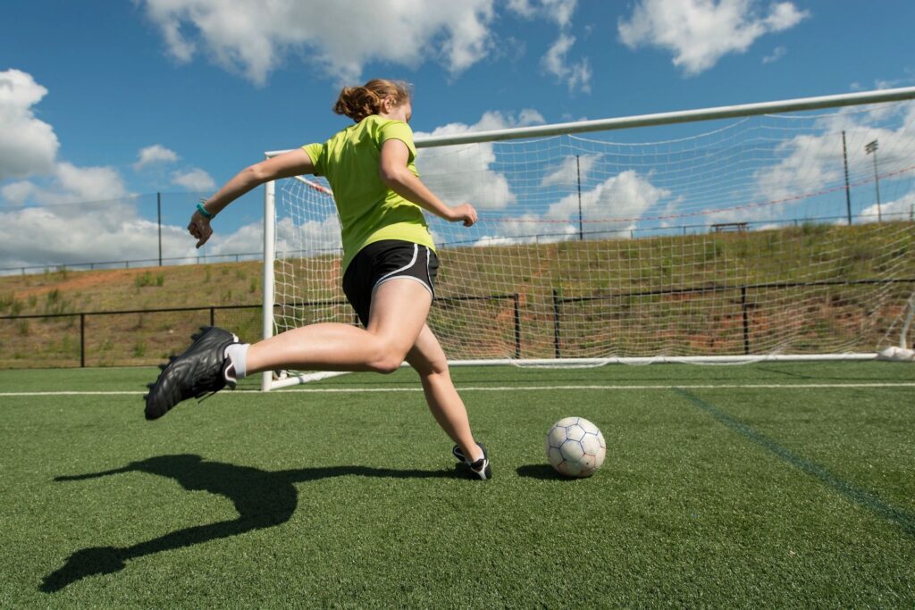 Soccer player kicking ball towards goal.