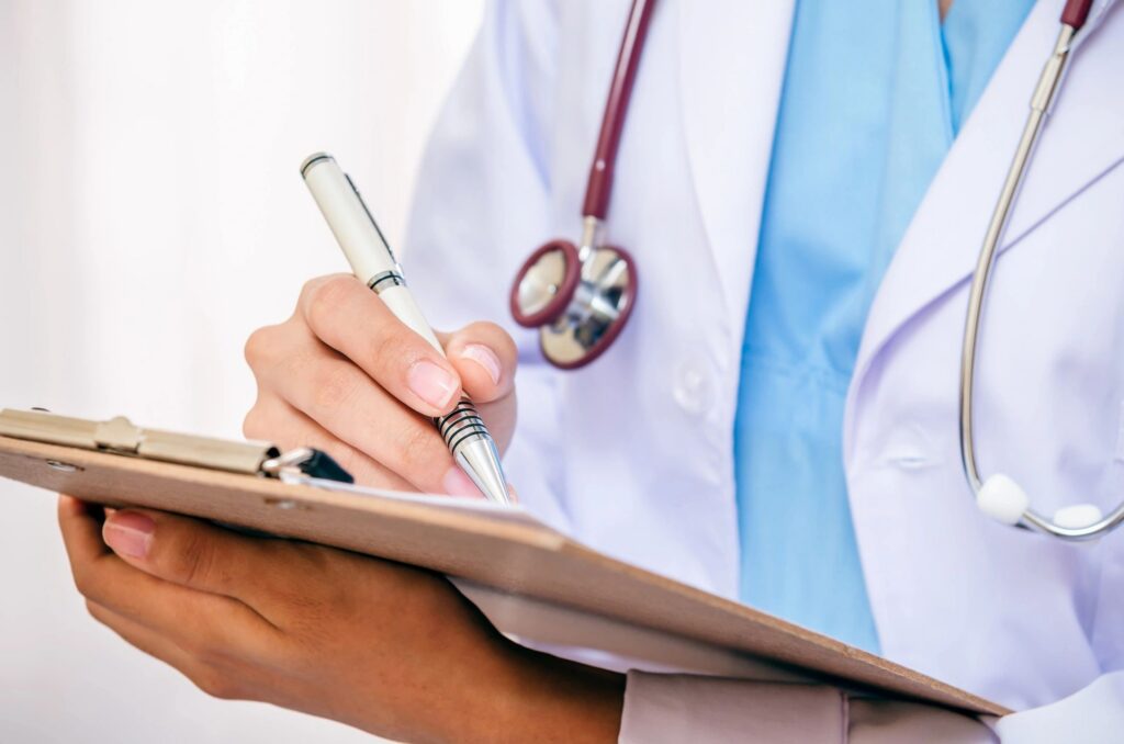 Doctor writing on a clipboard with stethoscope.