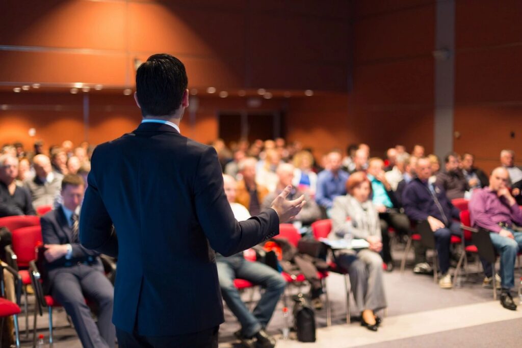 Speaker addressing audience in a conference room.