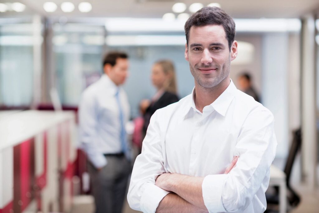 Smiling man in office with colleagues talking.
