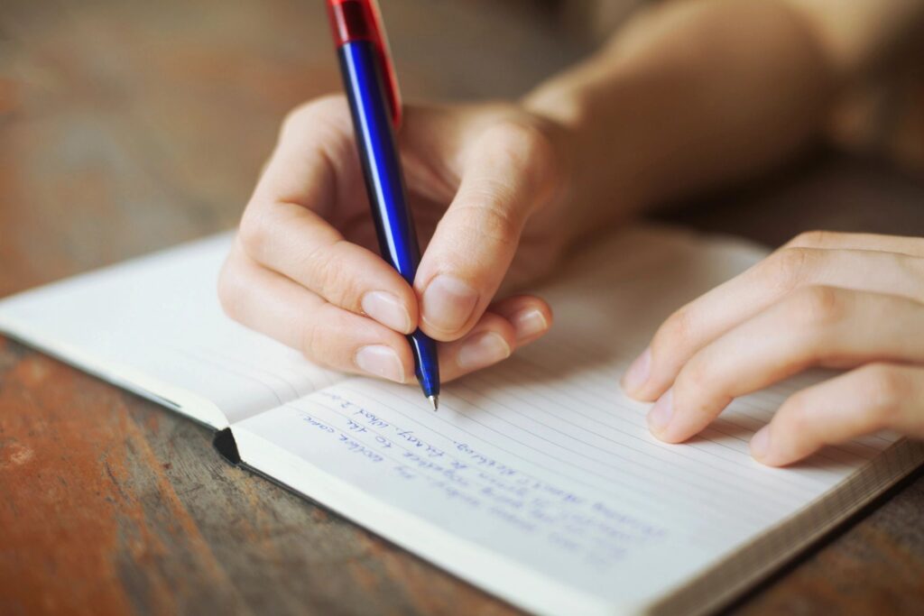 Hand writing in a notebook with pen.
