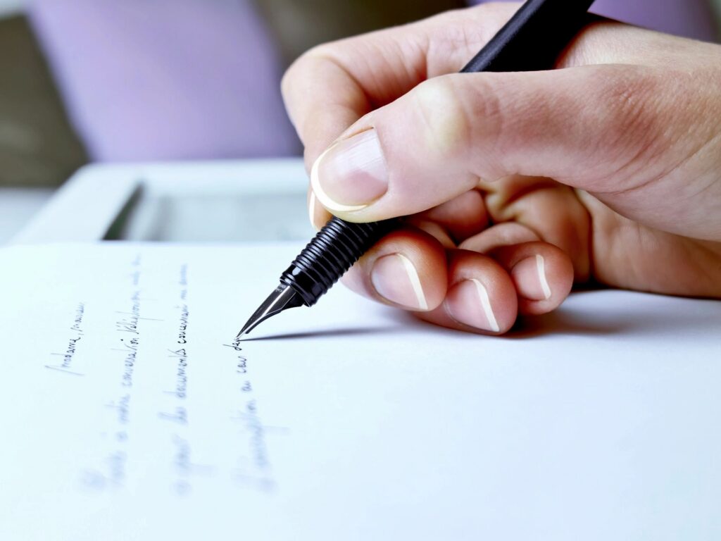 Hand writing on paper with black pen.