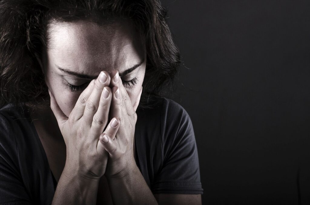 Person covering face with hands, appearing distressed.
