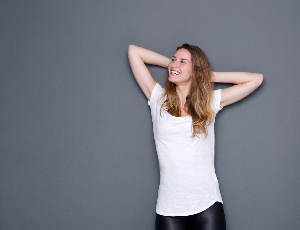 Smiling woman in white shirt, hands up.
