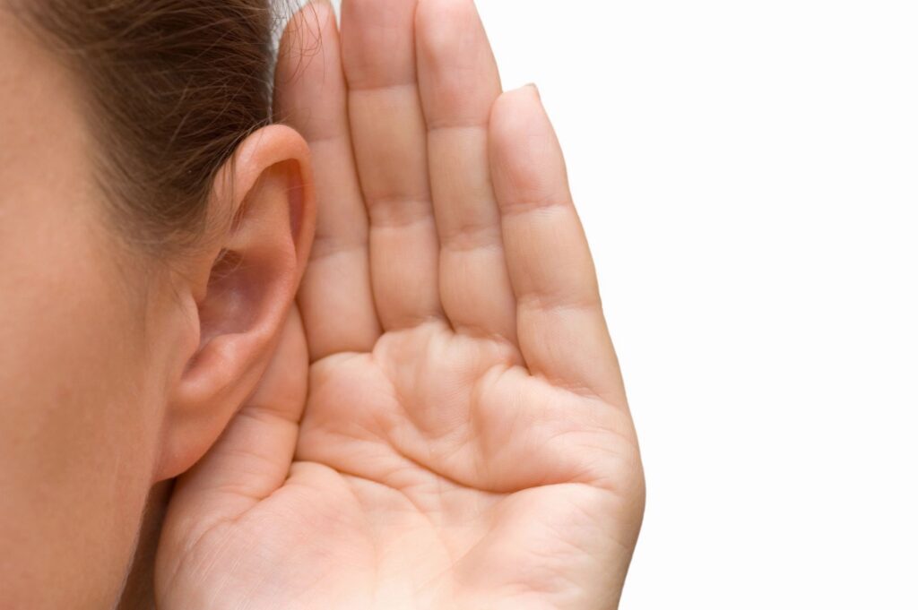 Person cupping ear, listening intently.