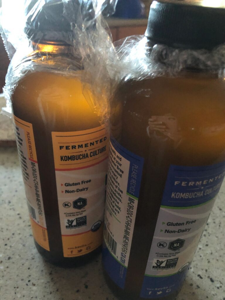Two bottles of kombucha culture on counter.