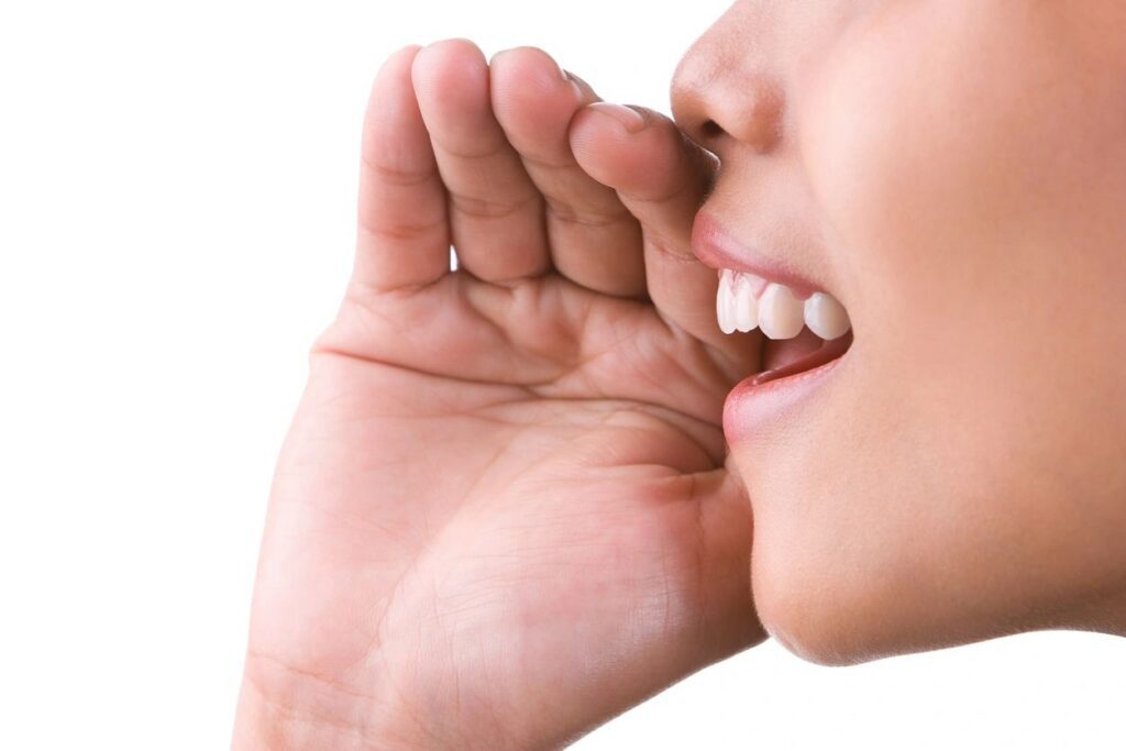 Person whispering with hand near mouth.