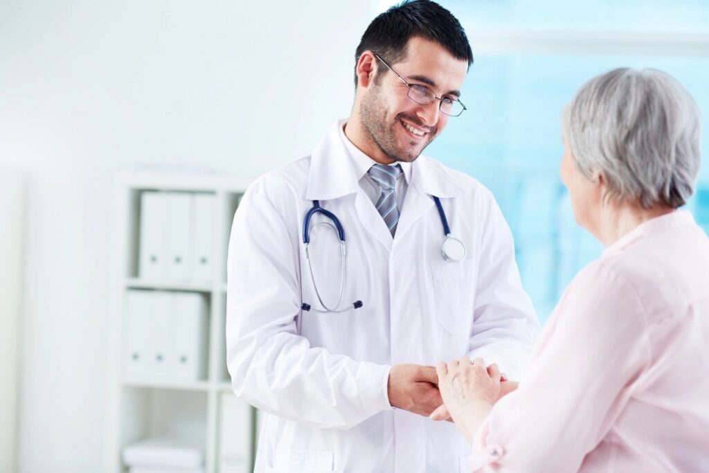 Doctor comforting elderly patient, smiling warmly.