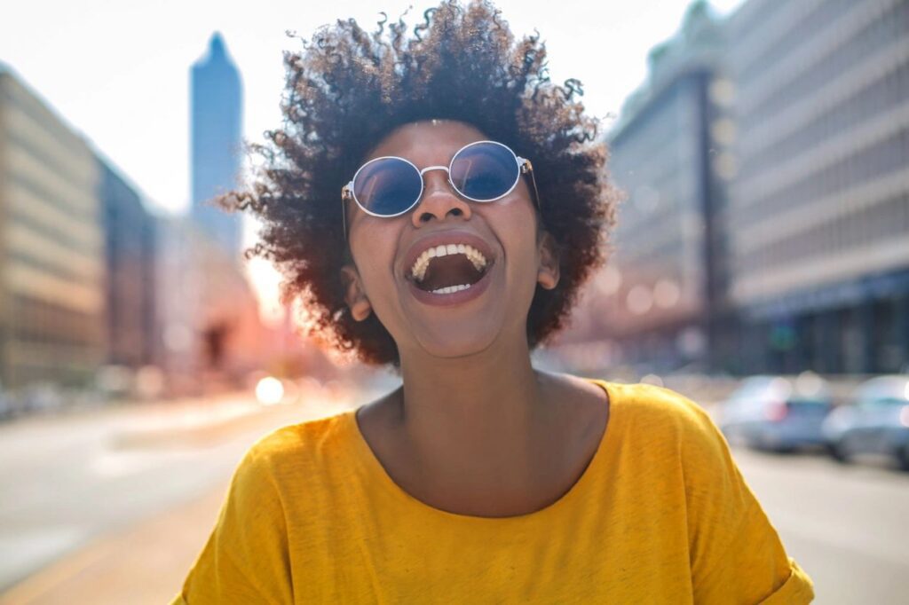 Smiling person wearing sunglasses on city street.