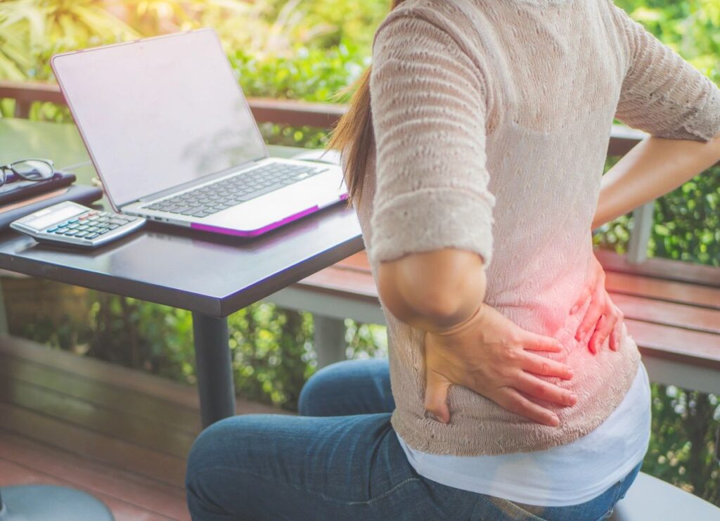 Person with back pain at outdoor desk.