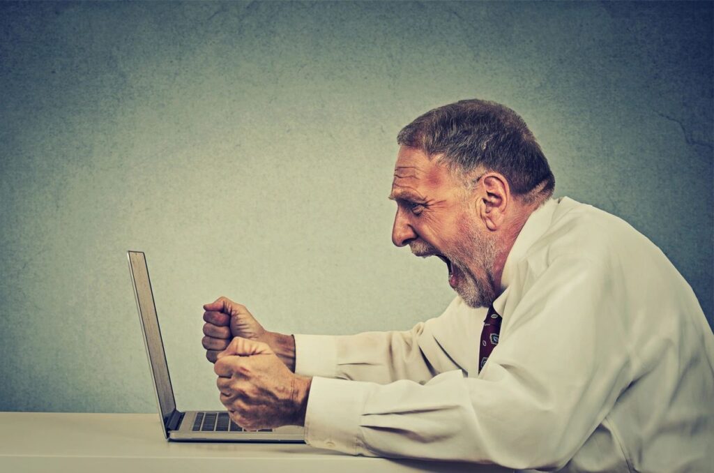 Elderly man frustrated at laptop screen.