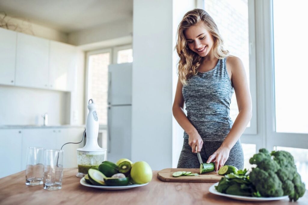 Woman slicing cucumber in modern kitchen.