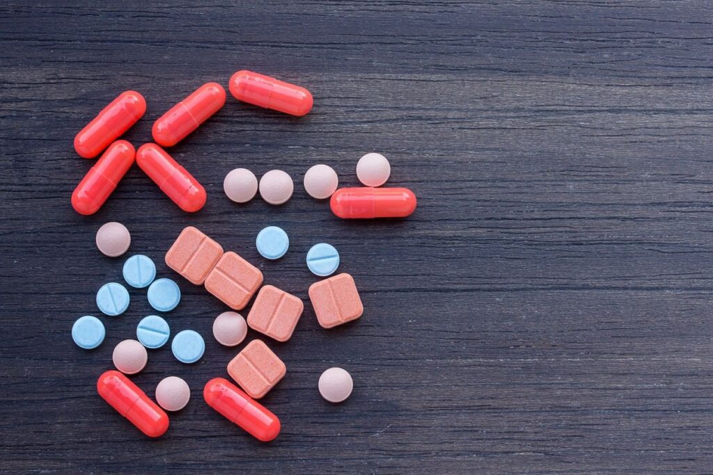 Various colorful pills on wooden surface.