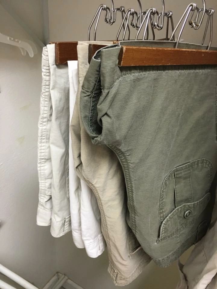 Shorts hanging on wooden hangers in closet.