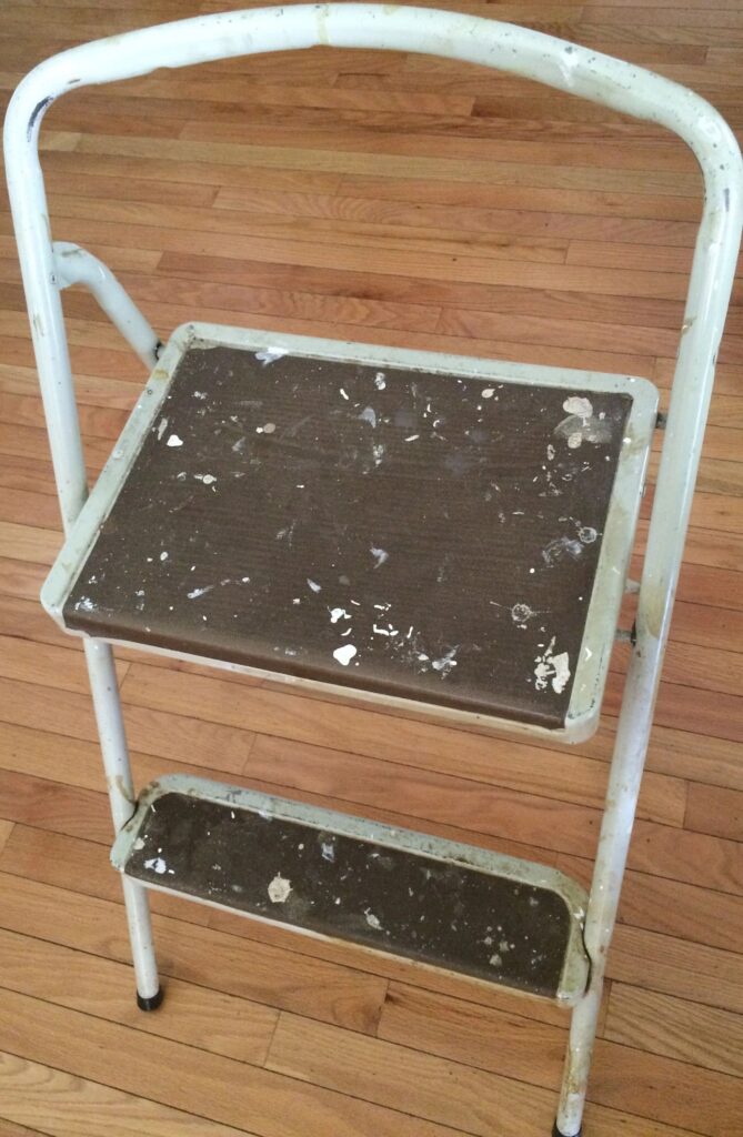 Weathered step stool on wooden floor.