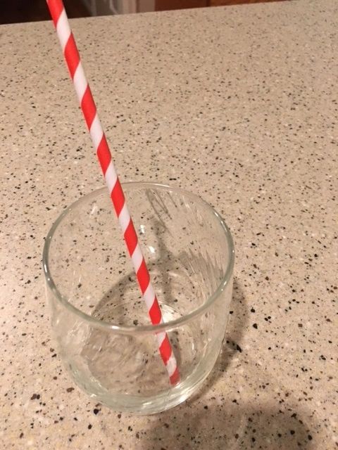 Empty glass with red striped straw.