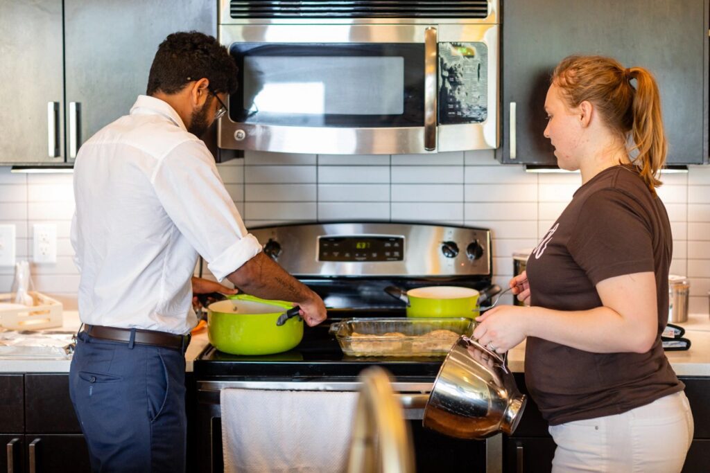 Two people cooking together in kitchen.