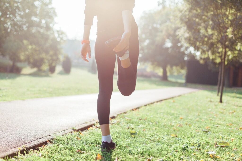 Person stretching in a sunny park.