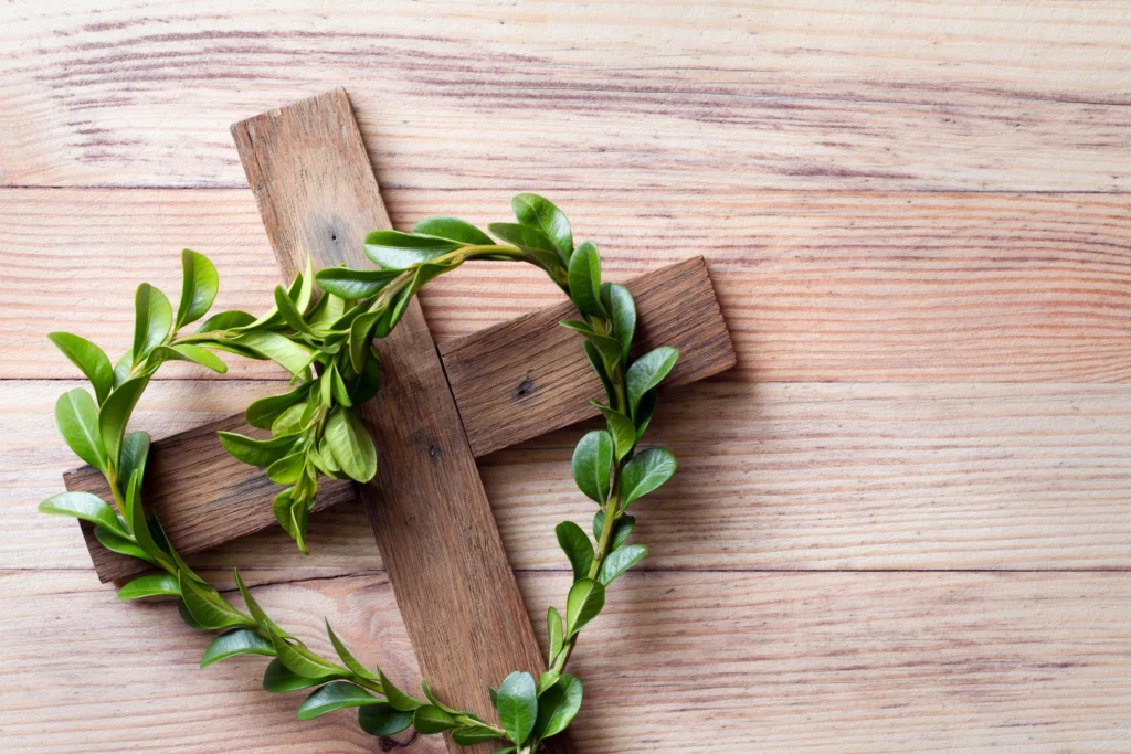 Wooden cross with a wreath of green leaves on top of it, symbolizing the resurrection