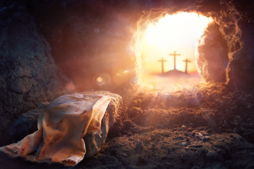 Person laying in a cave with a blanket draped over them, surrounded by stones