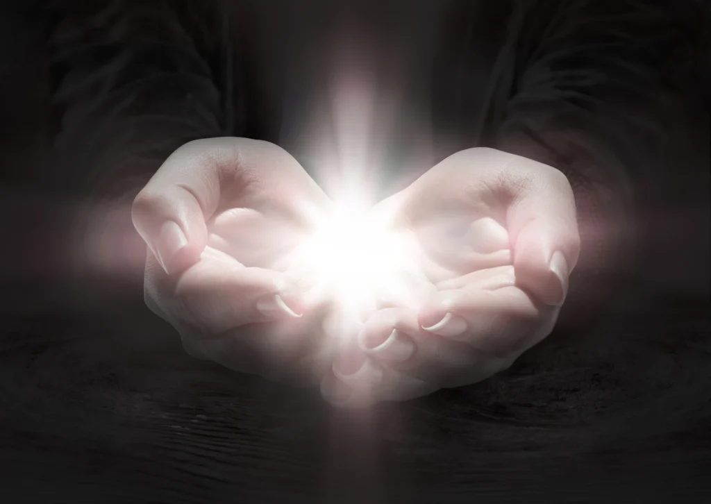 Person holding a light in their hands, illuminated by a bright light emanating from their palms