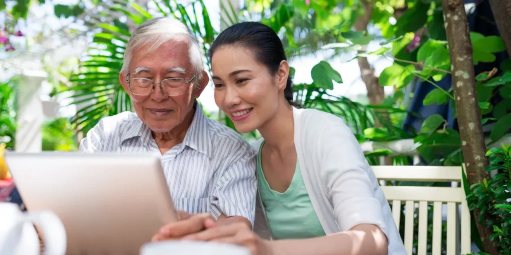 Older man and woman sitting at a table, looking intently at a laptop