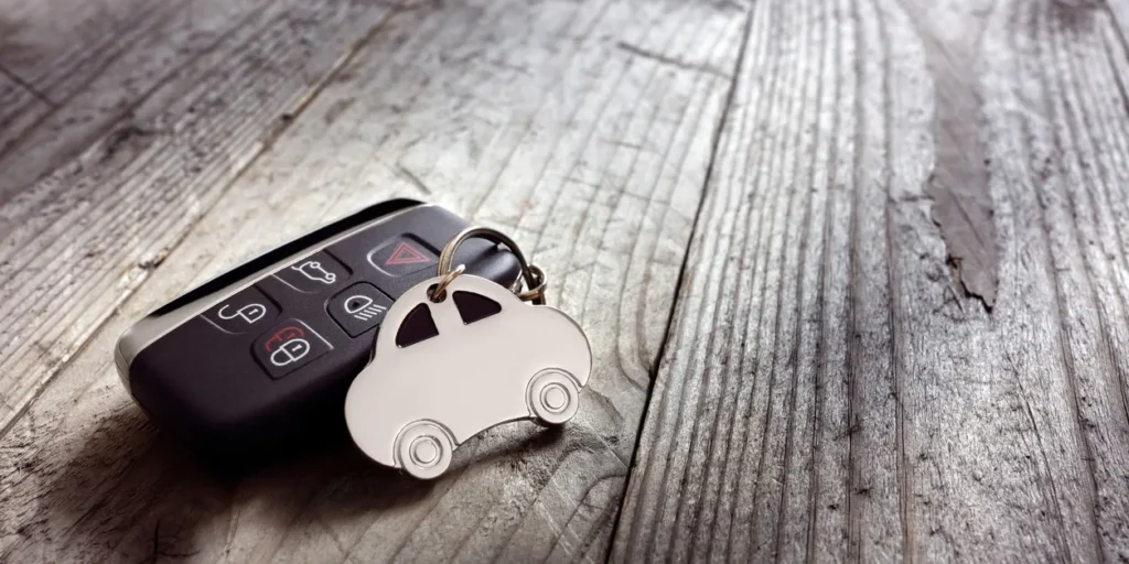Car key sitting atop a wooden table, with a keychain attached to it
