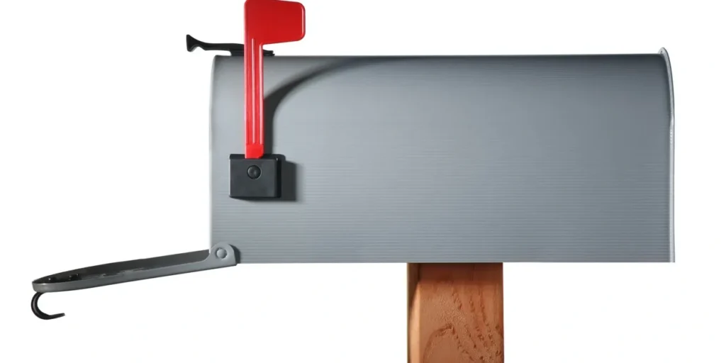 Gray mailbox with a red handle attached to a wooden post, providing a secure and reliable way to open