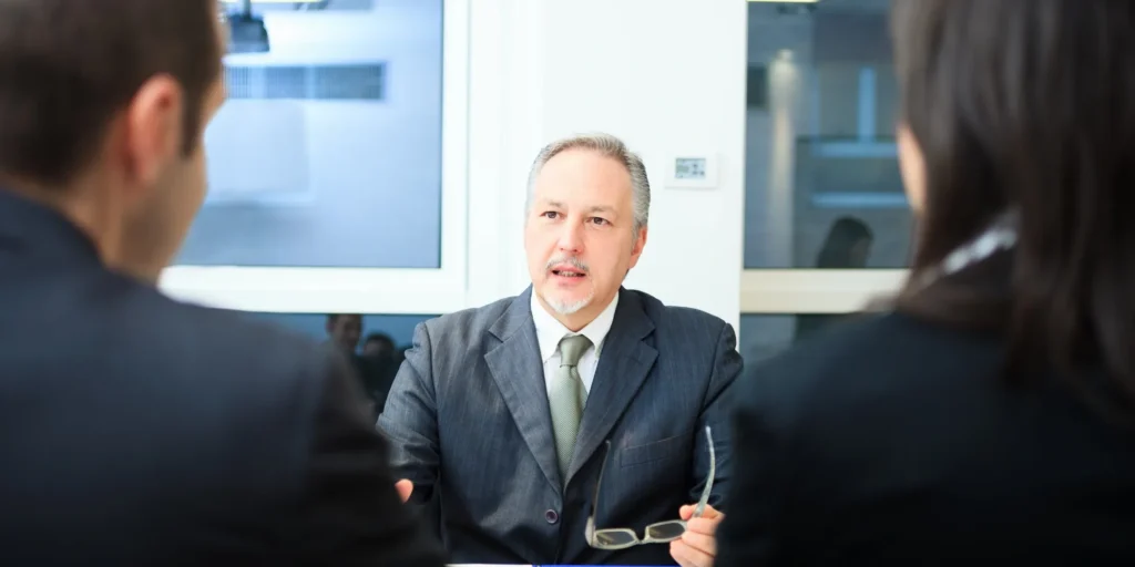 Man in a suit sitting at a table talking to two women