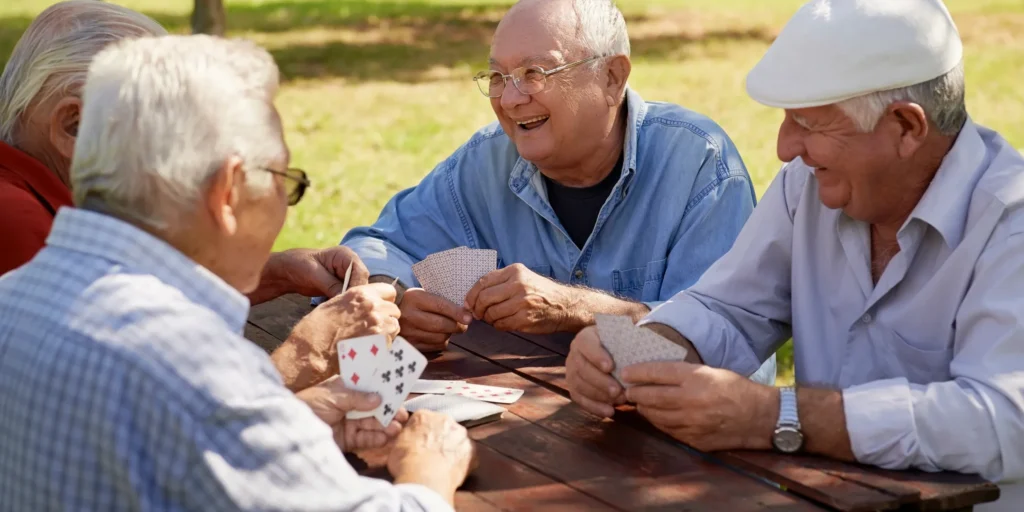 Four older men sitting around a wooden table, playing cards