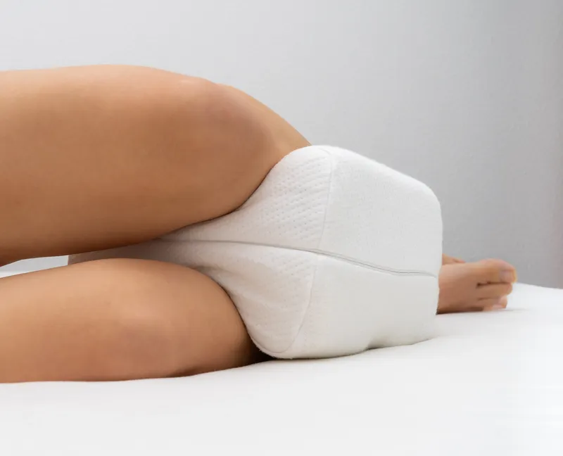 Woman laying on top of a white bed with a white pillow