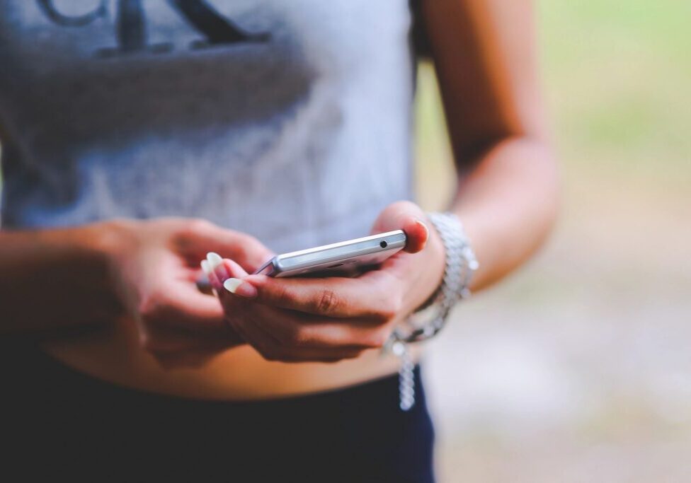 Person texting on a smartphone, wearing jewelry.