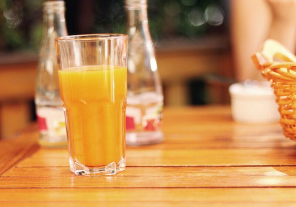 Glass of orange juice on wooden table.