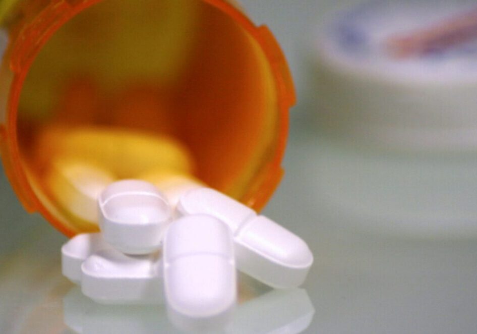 Prescription pills spilling from orange bottle.
