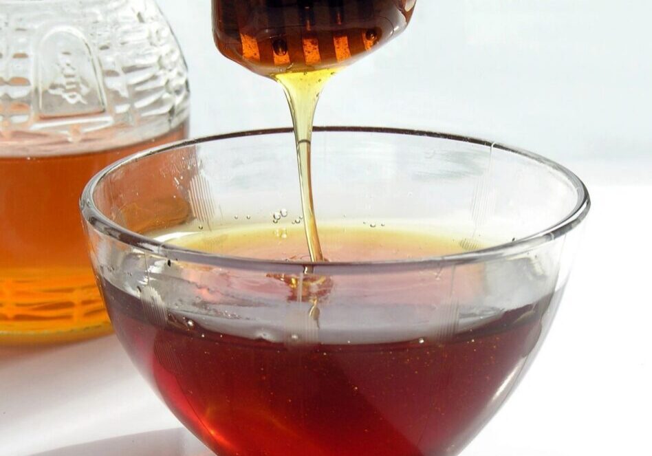 Honey drizzling into a glass bowl.