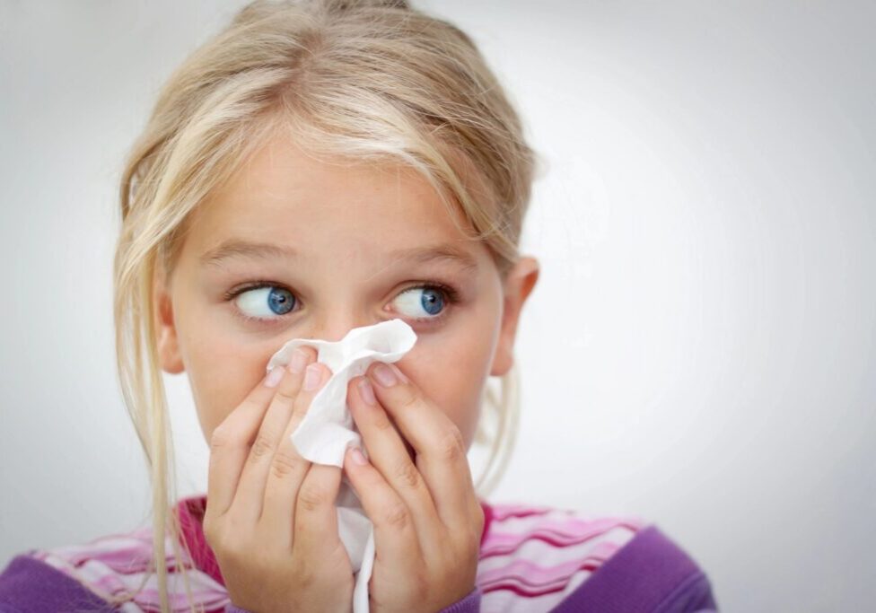 Child blowing nose with tissue paper.
