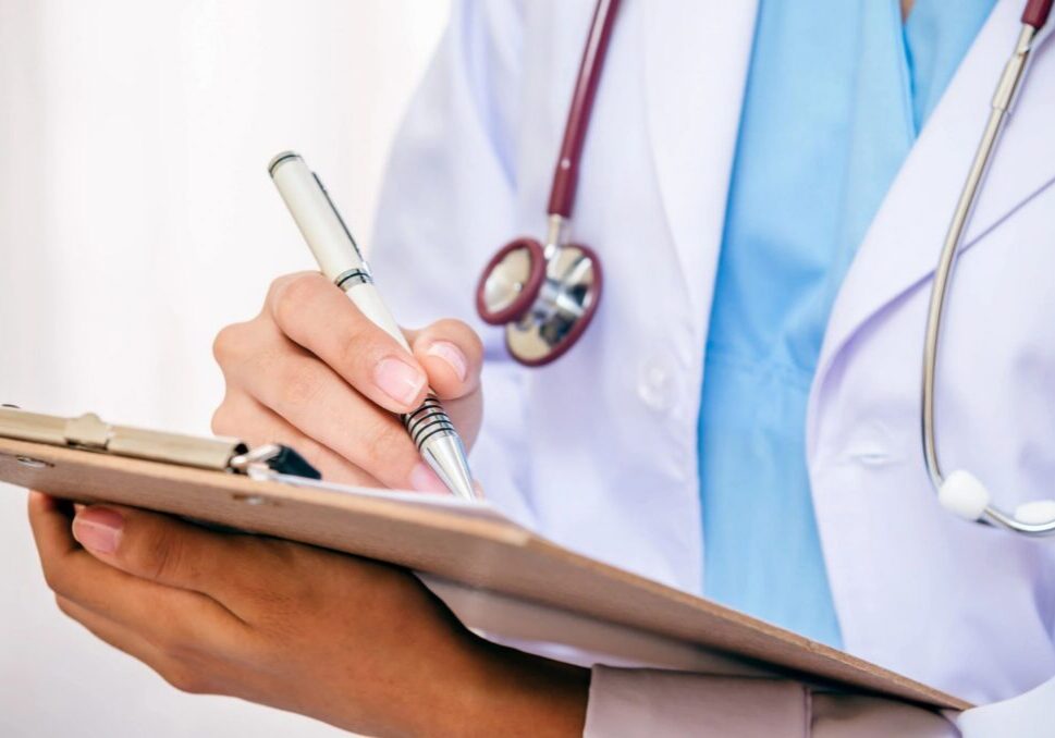 Doctor writing on a clipboard with stethoscope.