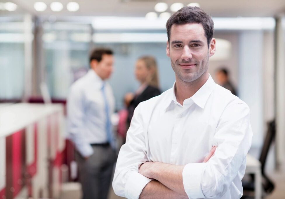 Smiling man in office with colleagues talking.