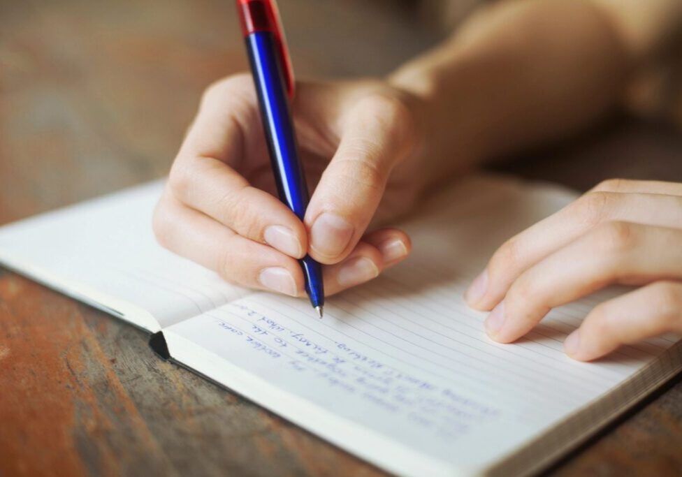 Hand writing in a notebook with pen.