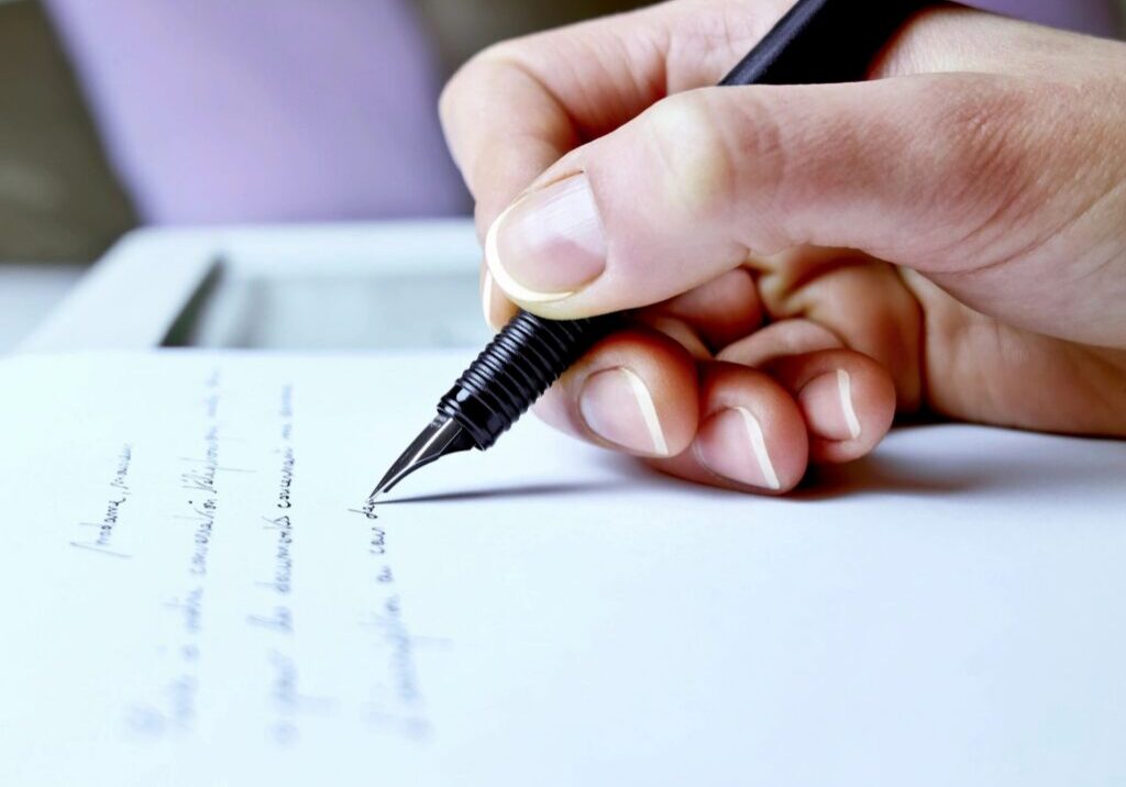 Hand writing on paper with black pen.
