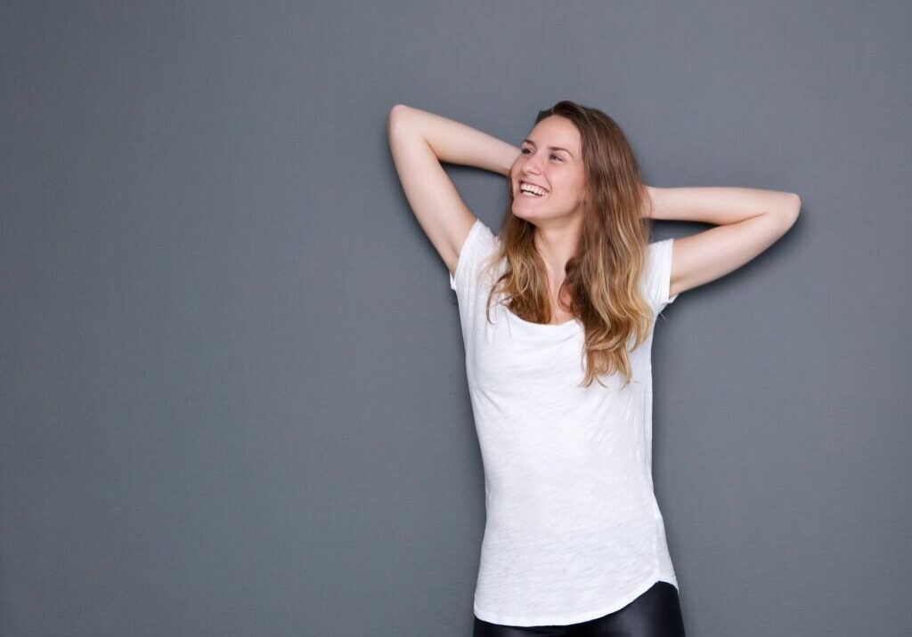 Smiling woman in white shirt, hands up.