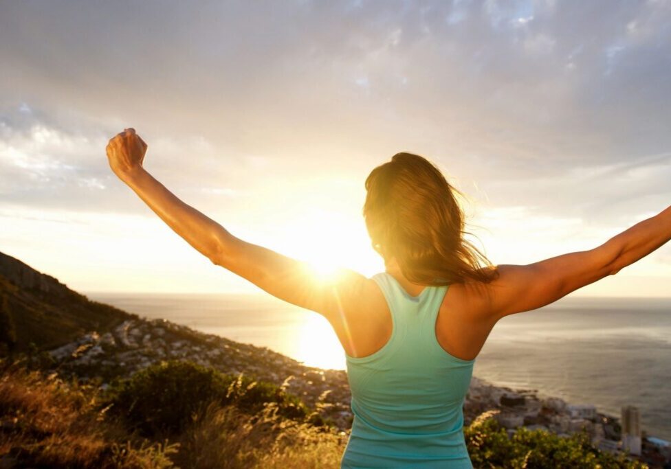 Person celebrating sunrise by the ocean.