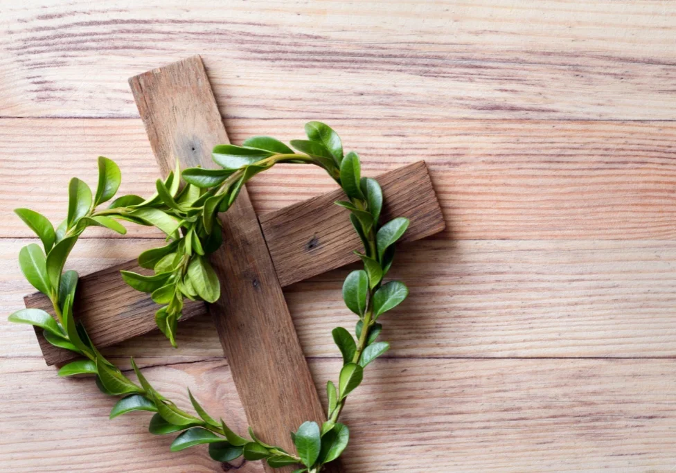 Wooden cross with a wreath of green leaves on top of it, symbolizing the resurrection