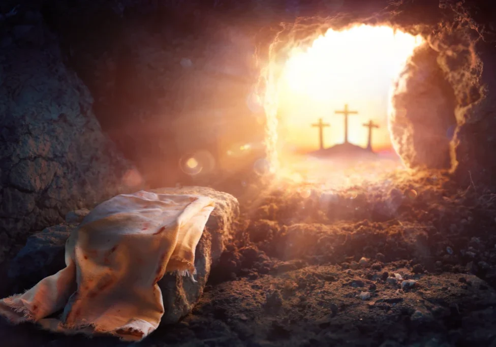 Person laying in a cave with a blanket draped over them, surrounded by stones