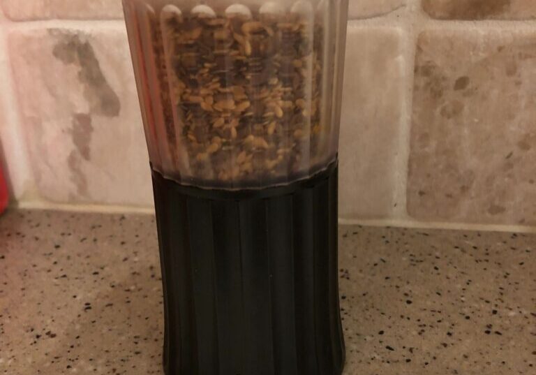 Black and clear spice grinder on countertop.