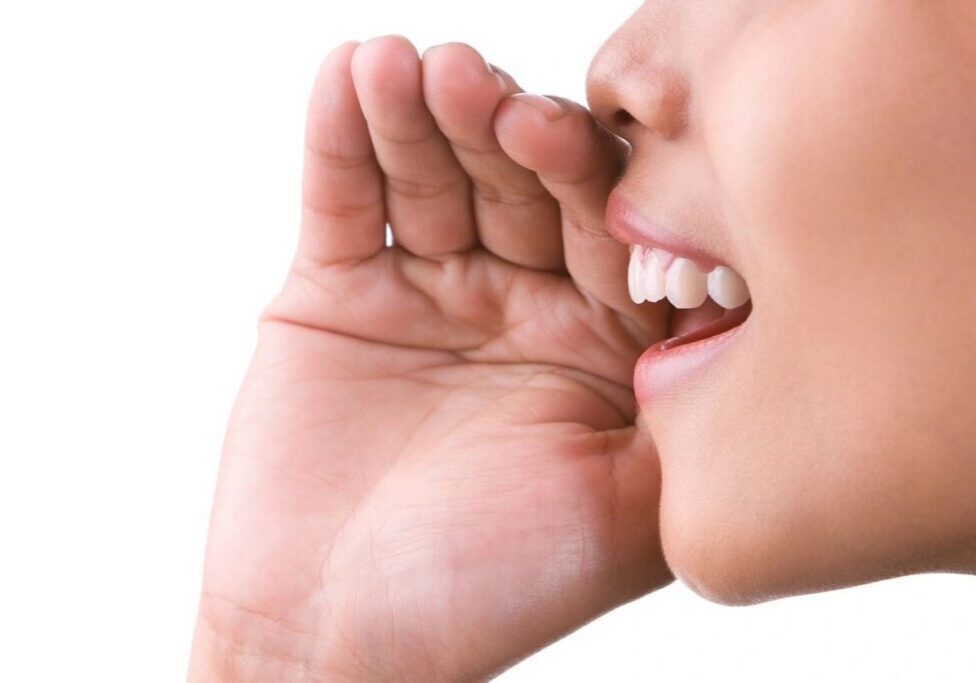 Person whispering with hand near mouth.